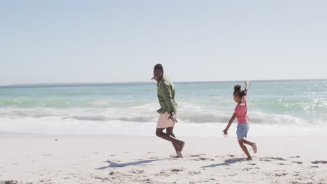 Padre-Afroamericano-Sonriente-Con-Su-Hija-Jugando-En-La-Playa-Soleada