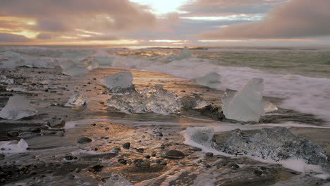 primer plano de la playa de arena negra con icebergs inundados por las olas del océano atlántico norte