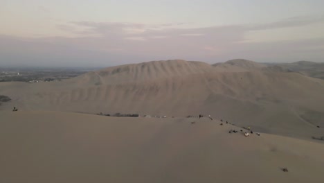 drone gracefully soars over the dunes, passing by people, revealing the oasis gem, huacachina