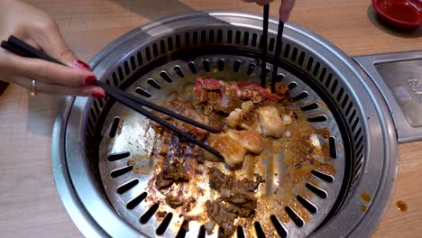 dory fish and beef is being cooked on hot pan by female chef with red nails