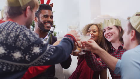 group of friends celebrating with champagne after enjoying christmas dinner at home