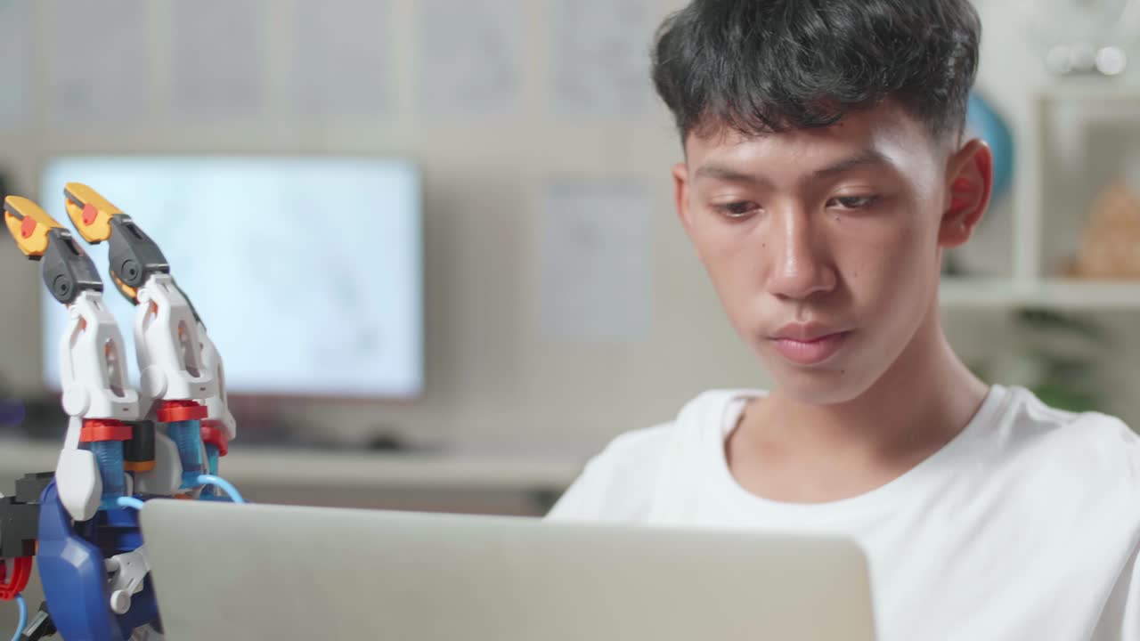 집에 있는 노트북에서 사이보그 손으로 작업하는 동안 생각하고 있는 아시아 소년의 클로즈업