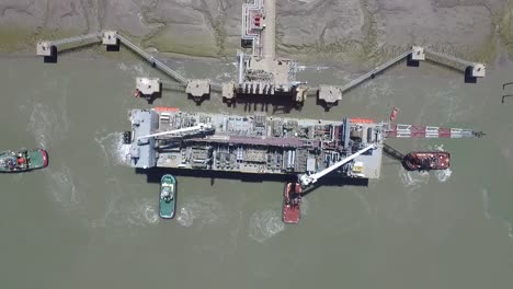 aerial view of cargo ship arriving at the port with the help of tugs