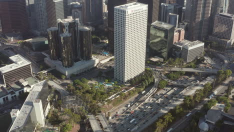 Tráfico-De-La-Autopista-Junto-Al-Horizonte-Del-Centro-De-Los-ángeles-En-El-Cielo-Azul-Día-Soleado-En-California,-Vista-De-Drones-Desde-El-Aire