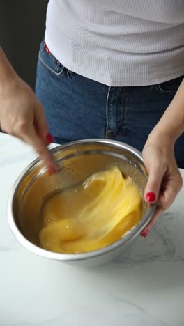 una mujer golpeando huevos en un cuenco para hornear.