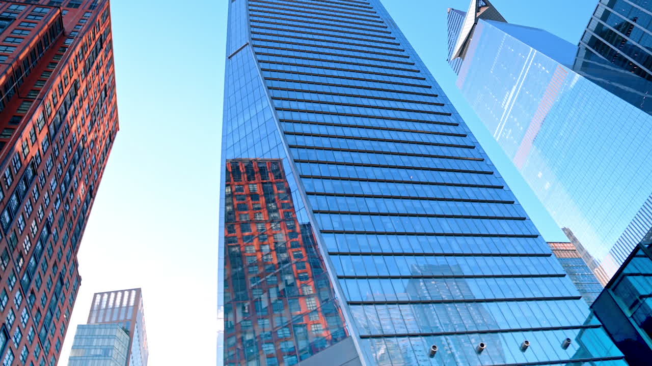 Glasbygninger i New York afspejler den blå, klare himmel på en solskinsdag. Beundring af den moderne arkitektur i en storby set fra en lav engel