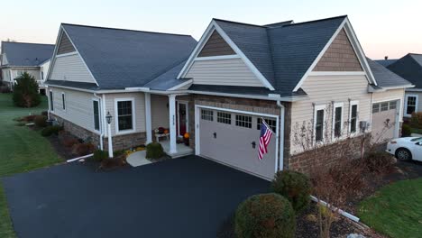 casa suburbana al amanecer con una bandera estadounidense en el garaje