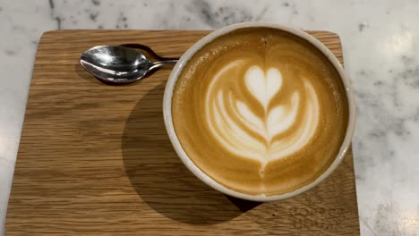 Close-up-of-coffee-cup-with-expertly-crafted-latte-art-atop,-steaming-and-inviting