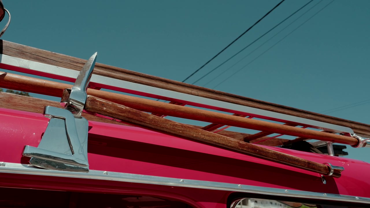 Chrome axe and wooden ladder mounted on the side of a red fire truck