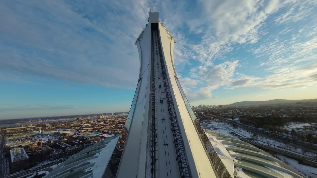 FPV drone captures Olympic Stadium with snow on rooftop at sunset, creating a wintry scene
