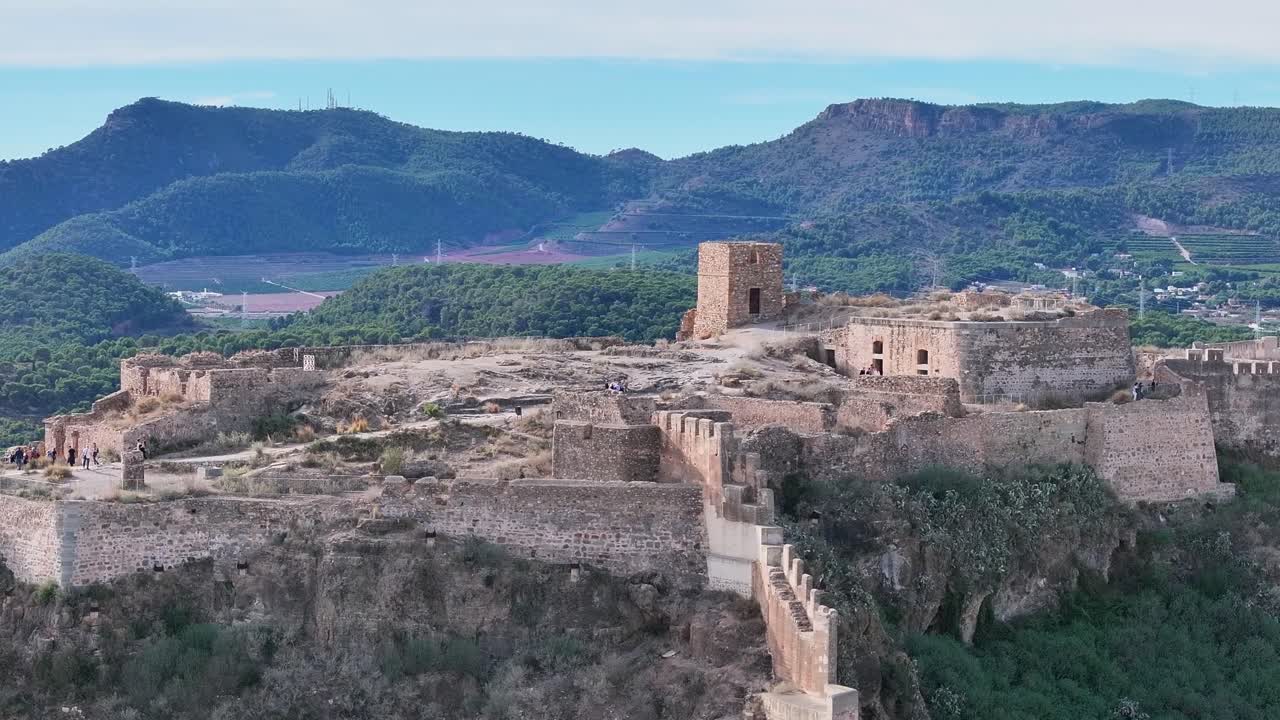 flight with a drone with parallax effect over the highest part of the fortress where there are people visiting it with a beautiful background of mountains and a blue sky on a morning Valencia Spain