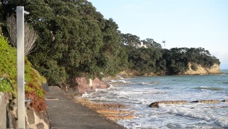 Costa-Rocosa-Y-Exuberante-En-La-Playa-De-Cuello-Angosto-Durante-La-Marea-Alta-En-La-Costa-Norte-De-Auckland