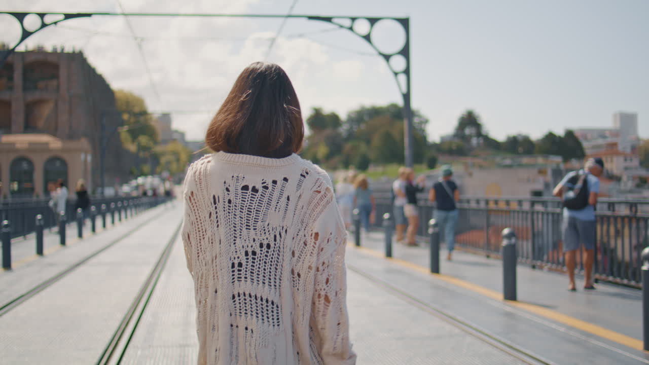 Laughing lady turning camera walking bridge back view. Carefree woman strolling