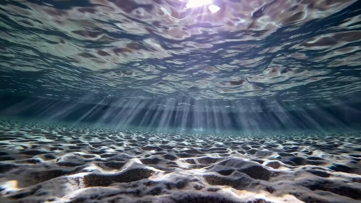 Onderwatervideo, opgenomen vanuit een lage hoek, die het zonlicht vastlegt dat door rimpelende golven filtert