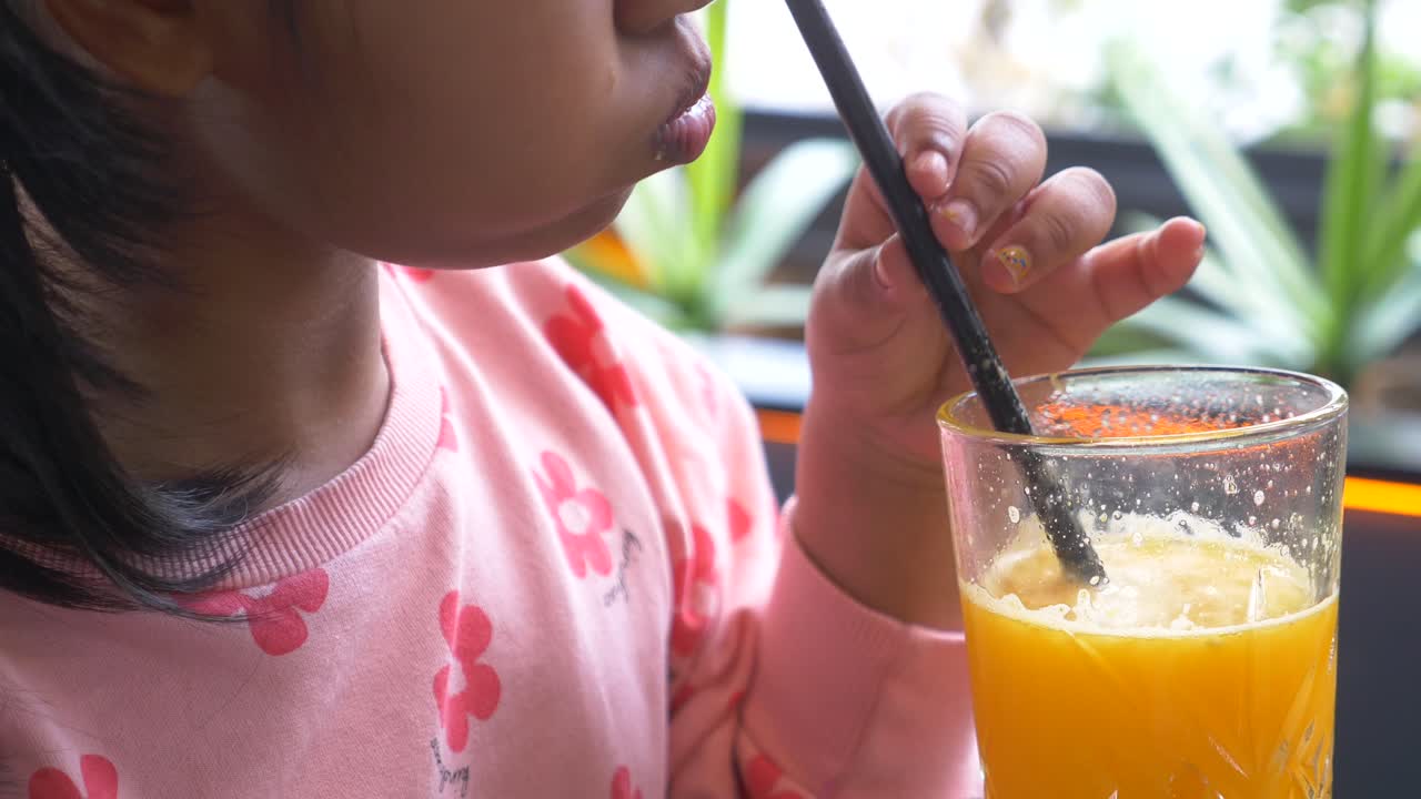una joven bebiendo jugo de naranja en un café