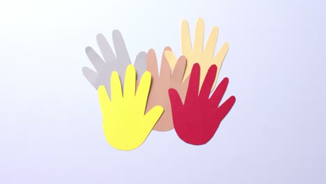 Close-up-of-hands-together-made-of-colourful-paper-on-white-background-with-copy-space