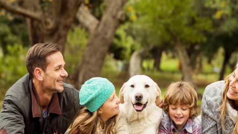 padres caucásicos felices, hijo e hija acostados con perros de compañía en el parque