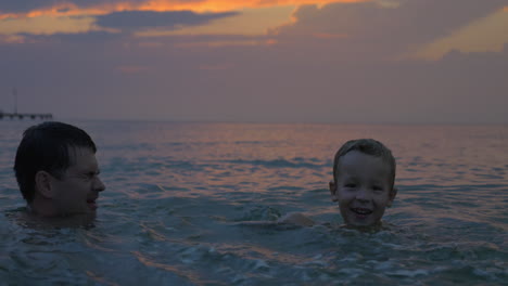 child and father having fun in the sea