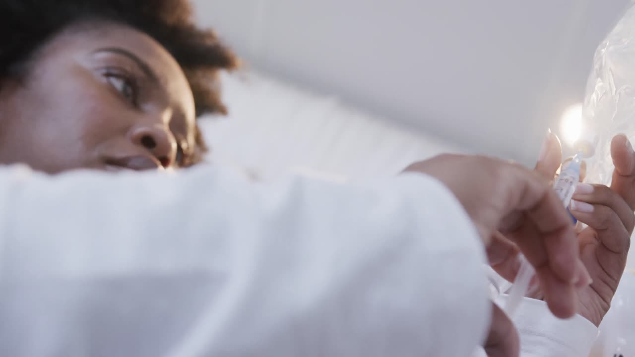 Dottoressa afroamericana che controlla una flebo in una stanza d'ospedale, al rallentatore