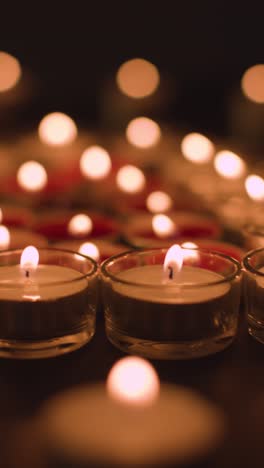 Vertical-Video-Close-Up-Shot-Of-Romantic-Red-And-White-Candles-In-the-Shape-Of-A-Heart-On-Black-Background