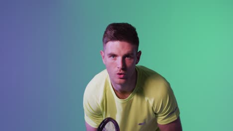 Portrait-of-caucasian-male-tennis-player-with-tennis-racket-playing-over-neon-green-lighting