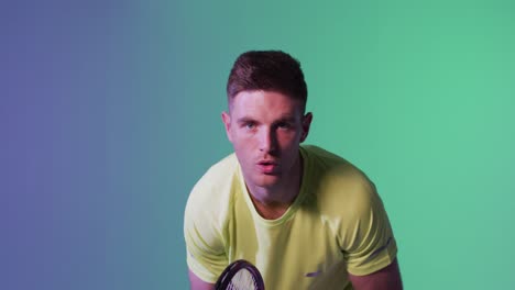 portrait of caucasian male tennis player with tennis racket playing over neon green lighting