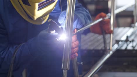 man wearing mask welding in a workshop. metal workers use manual labor. skilled welder. welder is welding the stainless steel pipes in the factory. welder industrial part in factory.