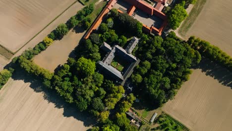 drone shot of a symmetrical monastery in surrounded by green tree's in a country landscape