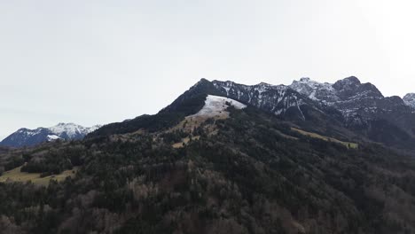 Aerial-View-from-late-Winter-Mountain-Landscape,-green-forest-and-snowy-mountains,-austria