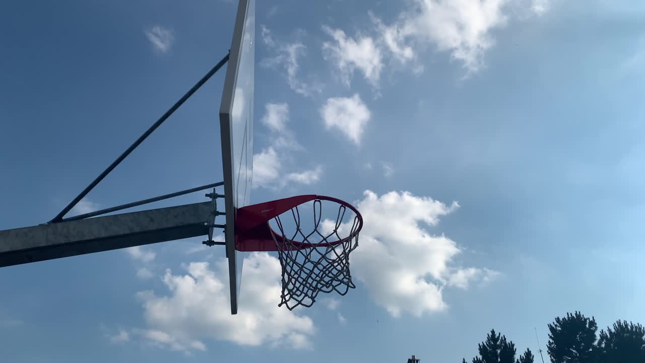 pelota de baloncesto entrando en el aro y cayendo a través de la red, contra el cielo azul