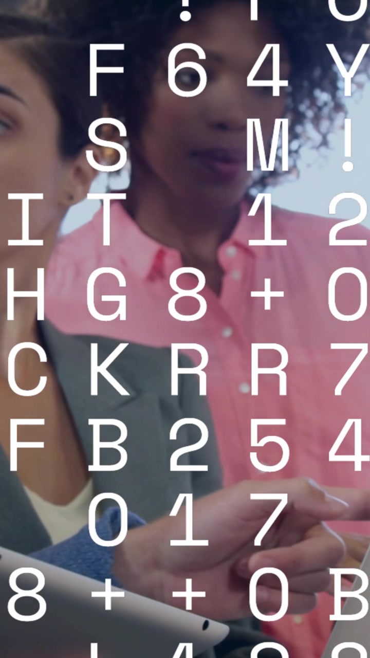 Vertical video: Woman typing while colleague leaning in, causing data overlay on laptop for tech
