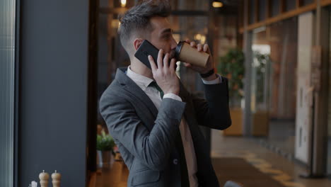 businessman talking on phone and drinking coffee in cafe