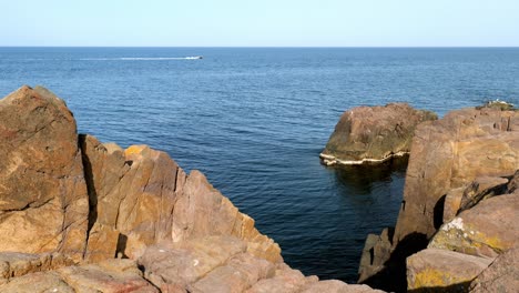 Distant-speed-boat-off-the-rocky-rugged-headland-of-Sozopol-Black-sea-coast