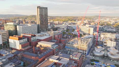 aerial approaching shot of sheffield city with construction site and cranes during sunny day