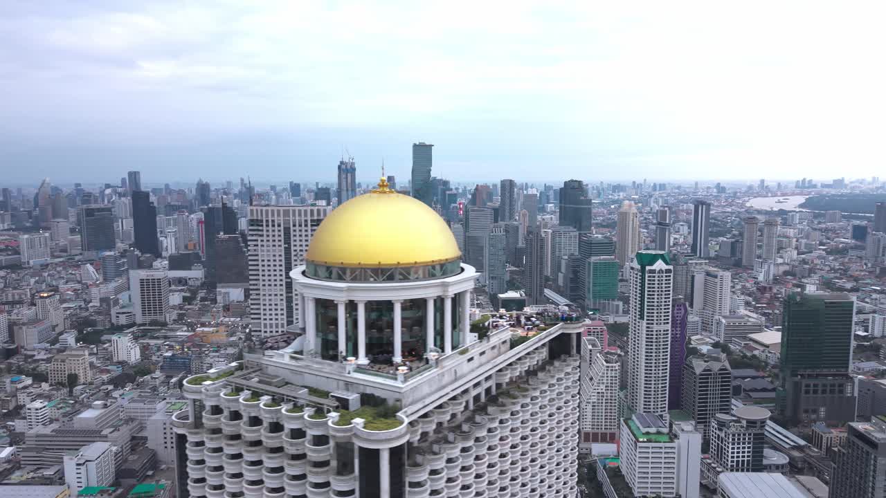 Vista aérea da State Tower erguendo-se sobre o horizonte de Bangkok, com sua cúpula dourada e design neoclássico destacando-se sobre o distrito do Rio Chao Phraya. (5)