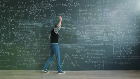 happy man crazy scientist writing formilas on board then dancing in class having fun