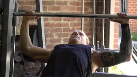 tattooed man in home gym close up shot smith machine incline bench press