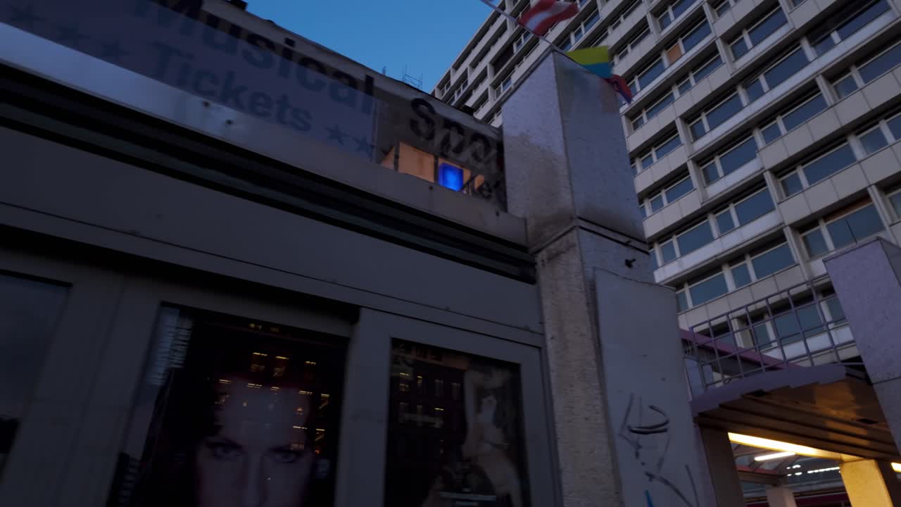 Evening scene of an illuminated U-Bahn station entrance in Berlin, Germany. People walking nearby creating a lively urban atmosphere.