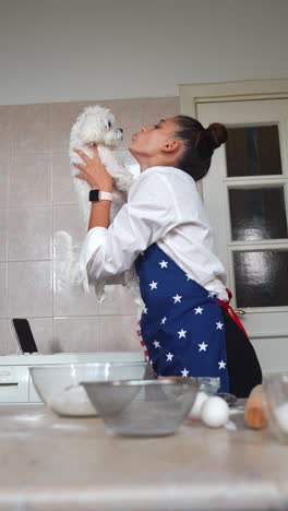 woman kissing dog in kitchen