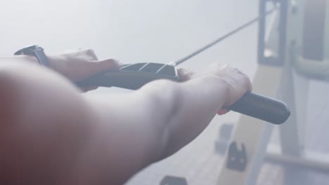 슬로우 모션으로 체육관에서 로잉 기계에서 훈련하는 아프리카계 미국인 여성의 중간 부분