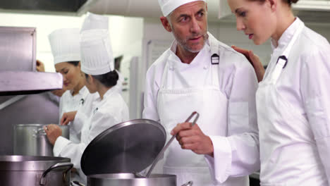 el chef freía verduras y luego checa a su colega.