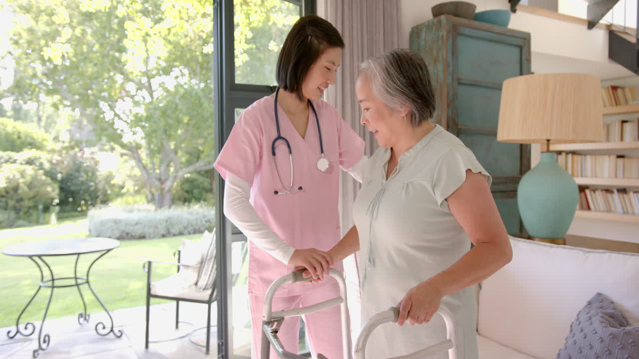 Senior asian woman exercising with resistance band, assisted by physiotherapist at home