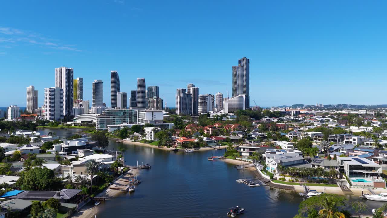 Drone footage captures Gold Coast's skyline and waterways under clear blue skies, showcasing urban architecture and natural beauty