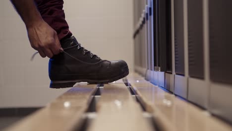 man tying the laces on leather boot over the wooden floor