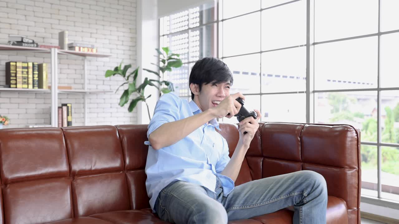 아시아 남자가 조이스틱을 들고 휴가 동안 tv에서 비디오 게임을 하고 있습니다.