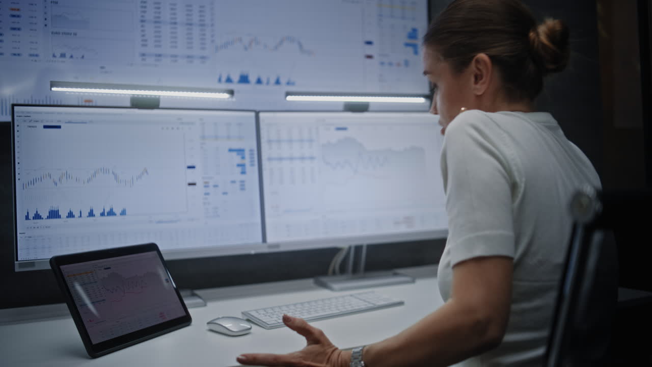 Businesswoman Analyzing Financial Data on Multiple Screens