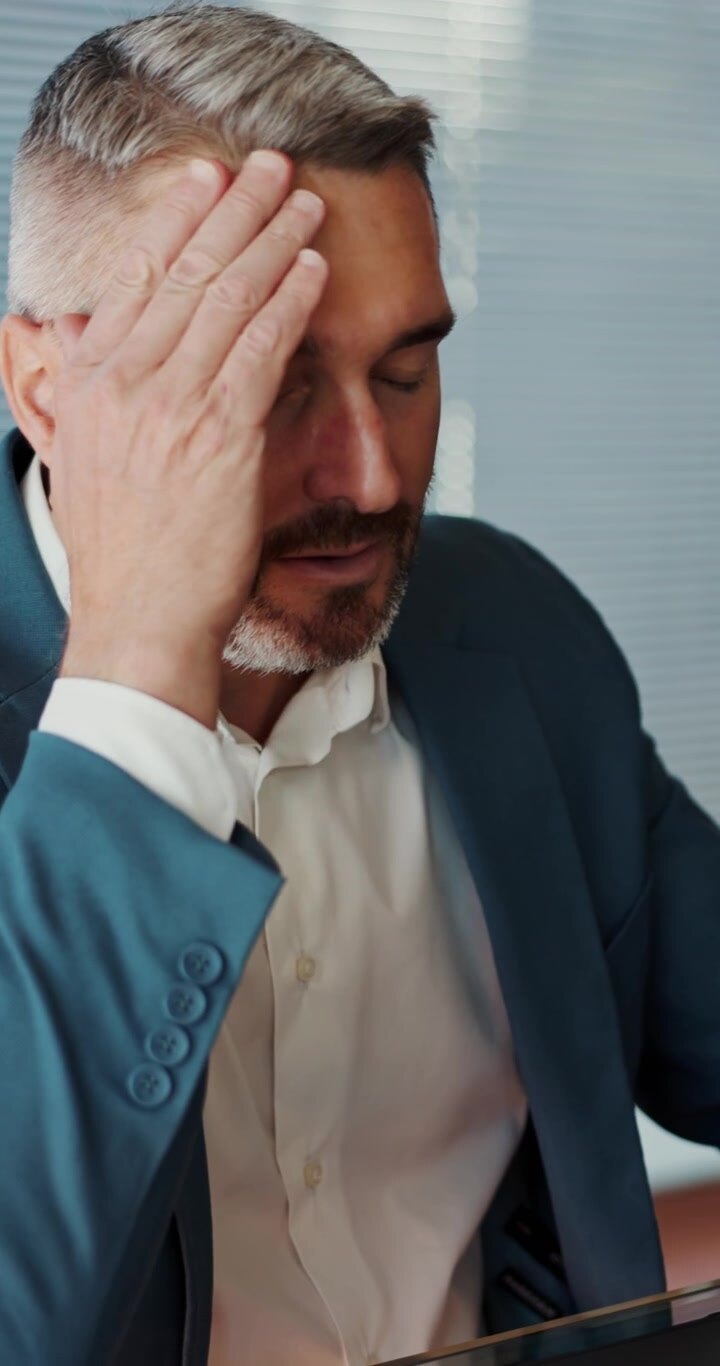Uomo d'affari stressato che si toglie gli occhiali e si strofina il viso in ufficio