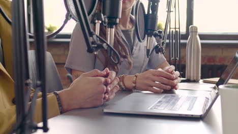 vista de cerca de las manos del hombre y las manos de la mujer gesticulando sobre la mesa mientras graban un podcast