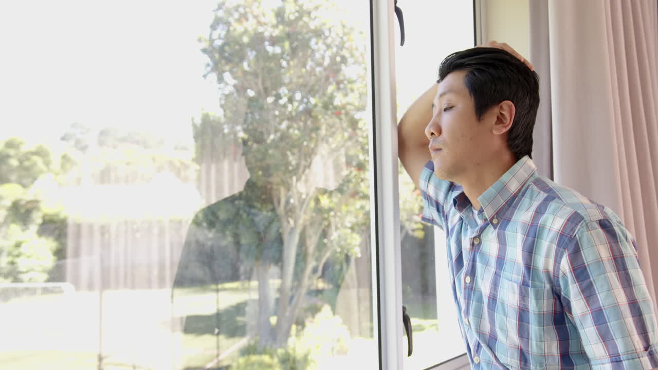 Looking out window, asian man in plaid shirt reflecting, hand on head, copy space