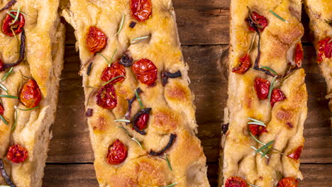 Traditional-Italian-Focaccia-with-pepperoni,-cherry-tomatoes,-black-olives,-rosemary-ando-onion---homemade-flat-bread-focaccia